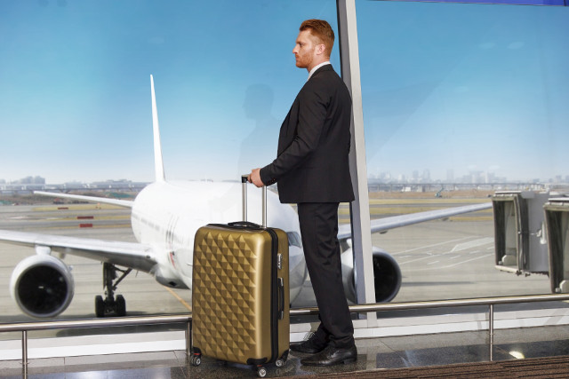 空港で旅行用スーツケースを持った男性